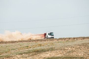 truck driving on sandy road picking up dust