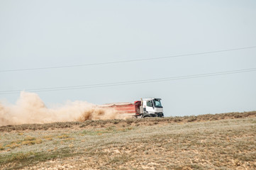 truck driving on sandy road picking up dust