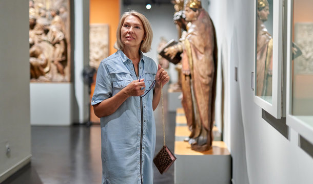 woman visitor looking at exhibition in museum of ancient sculpture.