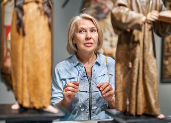 Mature woman visitor looking art object in art gallery museum.