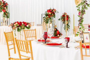 Beautiful banquet hall under a tent for a wedding reception. Interior of a wedding tent decoration ready for guests. Decor flowers. Red theme