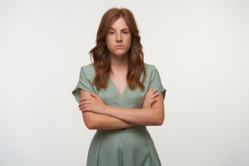 Obraz premium Attractive young redhead female standing over white background with crossed arms on her chest, raising eyebrow and having incredulous look
