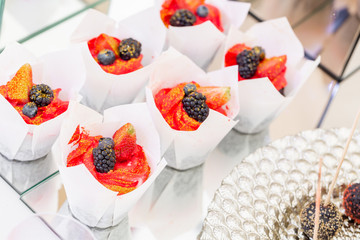 Red delicious muffin with blackberries and blueberries. Candy bar with a lot of desserts, meringue, cupcake, fruit and sweet cakes. Sweet table for birthday or wedding.