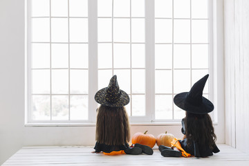Girls in Halloween costumes sitting near window