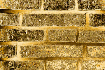 Golden brick wall. The texture of the ancient brickwork of the palace wall, painted in gold