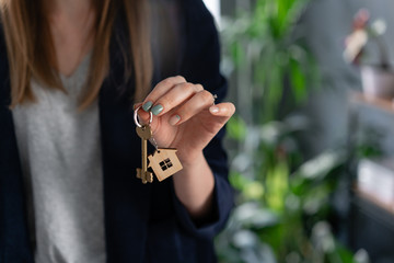 Mortgage concept. Young pretty woman. two house keys in womans hands. . Modern light lobby interior. Real estate, hypothec, moving home or renting property.