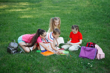 Teenagers sitting, talk and play on the green grass.