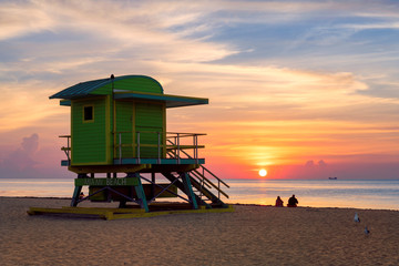 Ocean sunrise with lifeguard tower and colorful cloud and blue sky, Miami South Beach, Florida.