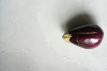 Trendy ugly organic eggplant on grey table, with copy space