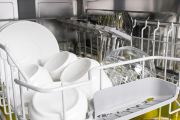 clean white dishes stand in the dishwasher, closeup background