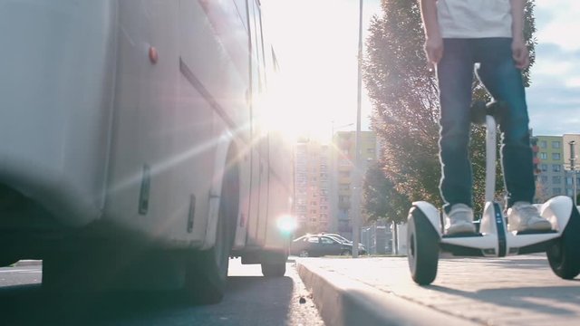 boy rides on a segway near the bus in the background of the sun