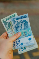 female hand holds banknotes of 500 (five hundred) and 100 (one hundred) Serbian dinars on a street in the city.