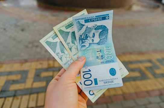 female hand holds banknotes of 500 (five hundred) and 100 (one hundred) Serbian dinars on a street in the city.