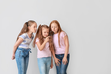 Obraz premium Little girls with magnifying glass on light background