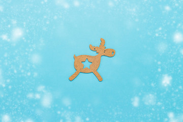 Wooden Christmas toy Deer on a blue background with snow. Concept of Merry Christmas and Happy New Year. Minimalistic style. Flat lay, top view