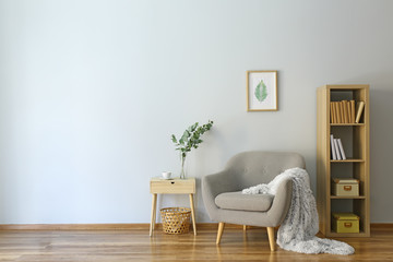 Stylish interior of room with armchair and eucalyptus branches in vase on table