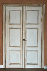 White door is closed. A dark handle is visible. Around pink the wall. Loft style or retro or vintage.