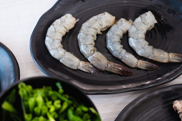 Top view of fresh raw shrimps on black plate preparing for cook at shabu shabu hotpot restaurant.