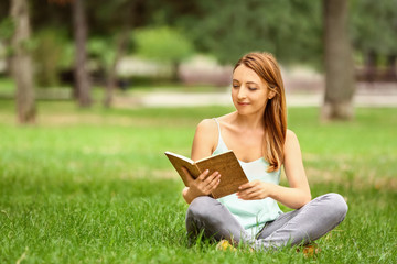 Obraz premium Woman reading book while relaxing in park