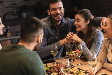 Group of young friends having fun in restaurant, talking and laughing while dining at table.