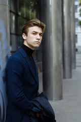 portrait of an attractive young man in a blue suit in the city