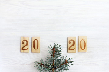 number plates and spruce branch on a light wooden table top view. happy new year 2020