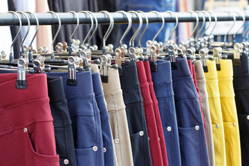 Multicolored casual pants hanging on hanger close up, side view - obrazy, fototapety, plakaty