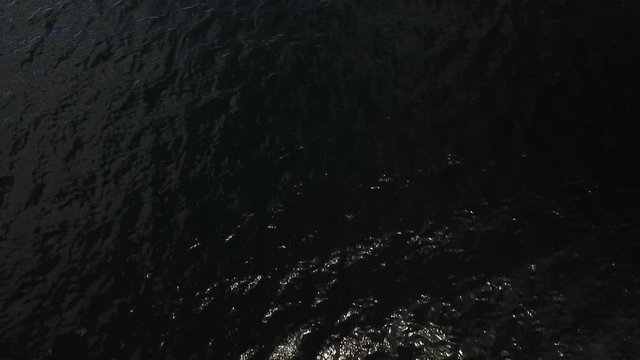 Aerial tilt down and up, moving forward low over lake water