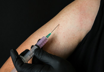 Man is getting an injection. Medical treatment of a low quality. Black gloves. Syringe with drugs.