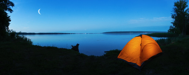 Orange tourist tent on shore of lake at dusk © alexlukin