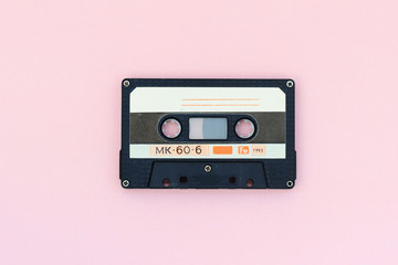Old audio tape cassette on a pink background. Top view, old technology concept