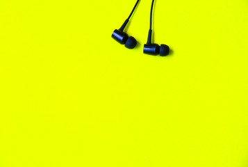 Earphones lying on the green background. Modern music concept. Audio technology.