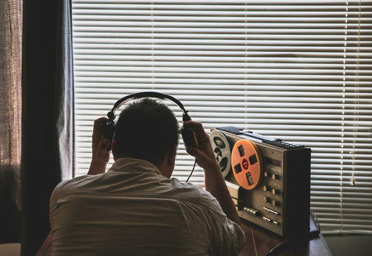 Special agent listens on the reel tape recorder. Officer wiretapping in headphones. KGB spying of conversations.