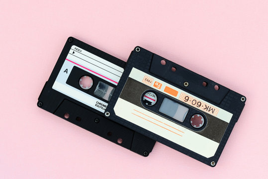 Old audio tape cassettes on a pink background. Top view, old technology concept