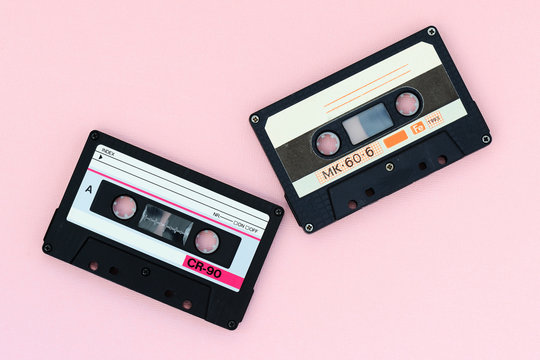 Old audio tape cassettes on a pink background. Top view, old technology concept