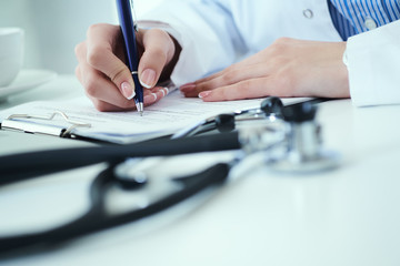Mid section of female doctor writes prescription to patient at worktable. Panacea and life save, prescribing treatment.