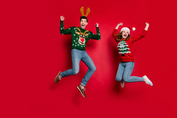 Full length photo of lady and guy jumping excited by x-mas discounts wear ugly ornament jumpers and...