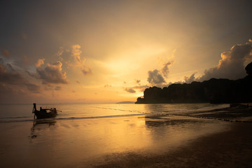 Amazing sunset with longtail boats silhouette at Railay beach, Thailand.