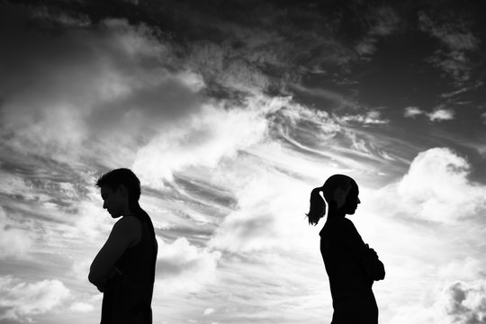 Silhouette of upset man and woman with backs turned away from each other. Couple fighting and not getting along concept. .