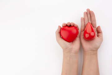 Two hands holding red blood drop and heart on white background. Give blood. Donation concept.