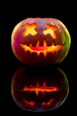 Halloween pumpkin head jack-o-lantern with scary evil face. Seasonal illuminated decoration. Looks scary, colorful neon light and dark background. Holidays. Black friday, sales. Night of fear.