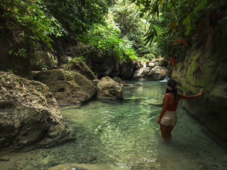 woman alone on the green canyon road at the middle of tropical jungle on the way of beautiful waterfall, Dao Falls in Cebu Island, Philippines