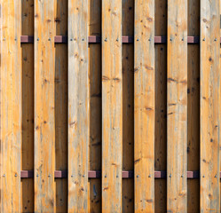 An unusual rustic old fence made of natural wooden spotted boards fixed on a brown metal bar with self-tapping screws. Abstract trendy texture background