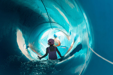 Two children on water slide at aquapark - obrazy, fototapety, plakaty