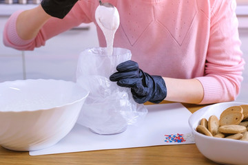 Woman's hands put the sugar sweet icing in the bag for decorating cookies and gingerbread houses