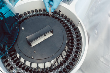 Lab technician loading centrifuge with tubes of human blood