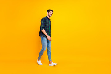 Fototapeta na wymiar Full length body size photo of cheerful attractive guy walking towards sales wearing sneakers isolated over yellow vivid color background