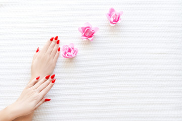 Red fashion manicure on delicate female hands. Hands of a beautiful young woman on a soft white background.