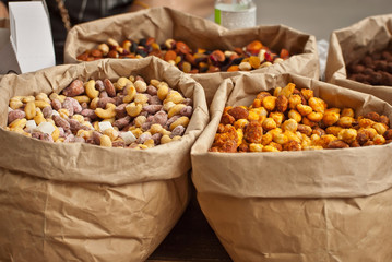 Many different nuts are sold at the fair. Nuts are sorted into paper bags.