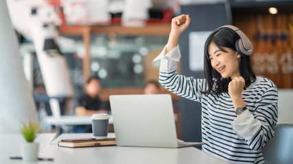 Beautiful Asian girl celebrate with laptop in office.